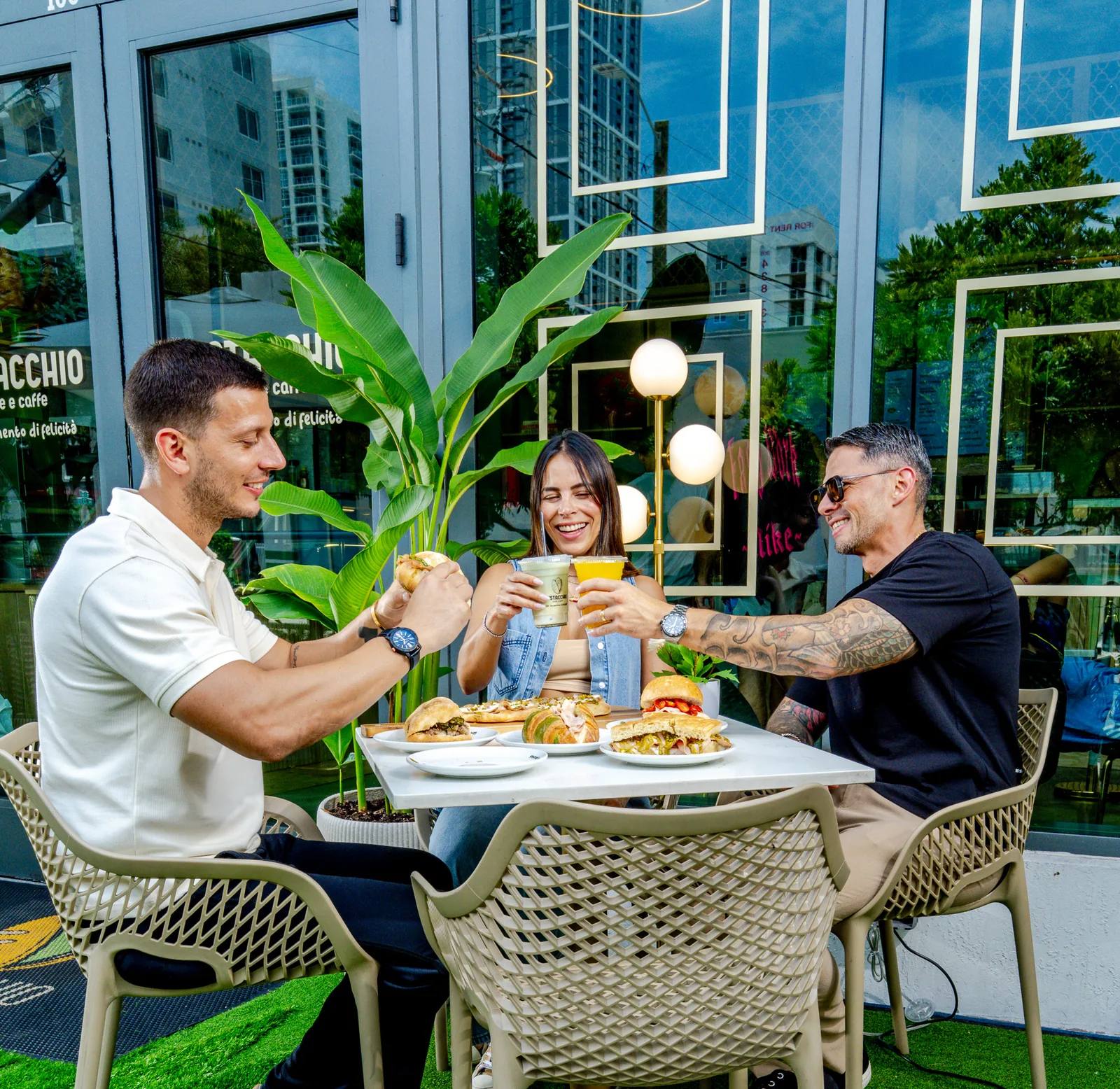 Amigos brindando con bebidas y paninis en Pistacchio, Miami
